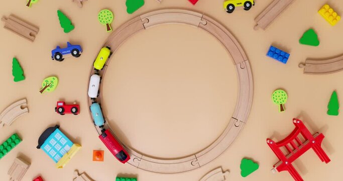 Toy wooden train with cars rides on round railroad on beige background