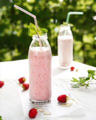 milkshake of strawberries and raspberries with mint, on a light table in the garden, close-up without people