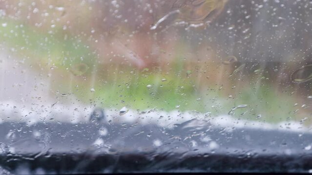 Hail and rain in late autumn. Bad weather on the field road. Hail was beating on the roof, and pounding on the windshield of the car and the windshield wipes are working