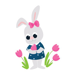 A very cute girl rabbit stands near flowers and holds a colored egg in her hands. Cartoon style characters isolated on white background for Happy Easter greeting cards. The Easter Bunny is very happy.