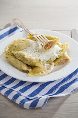 cooked dumplings with meat, spices and sour cream, in a plate on a light wooden table.