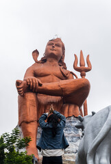 young girl paying salutation to hindu god lord shiva statue at morning from flat angle