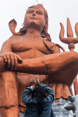young girl paying salutation to hindu god lord shiva statue at morning from flat angle