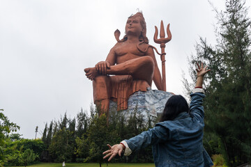 devotee praying to the hindu god lord shiva huge isolated statue at morning