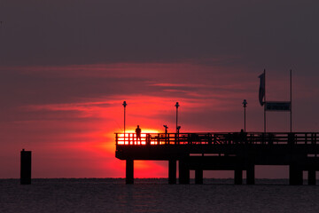 Fischer im Sonnenuntergang auf einer Seebrücke  - obrazy, fototapety, plakaty