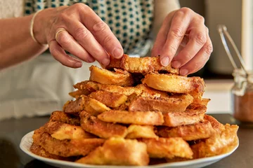 Foto op Canvas Close up of senior woman hands stacking easter and lent dessert. Traditional spanish recipe of torrijas or torrejas © Komuso & Colorsandia