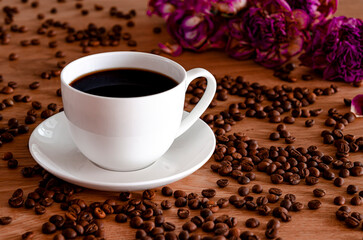A white porcelain cup with black coffee stands on a wooden table.