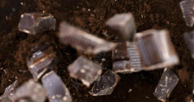 Super slow motion macro of raw bio organic dark bitter chocolate bar chunks are flying with cocoa powder particles at 1000 fps.