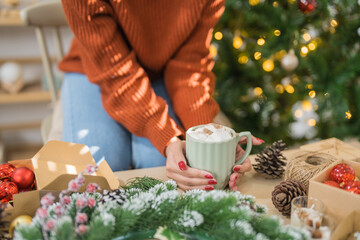 Woman holding cup of aromatic cocoa with marshmallows. Christmas eve with cup of tasty hot chocolate cozy holiday atmosphere at home