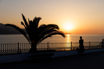 Person enjoying sunrise early in the morning in Nerja, Spain