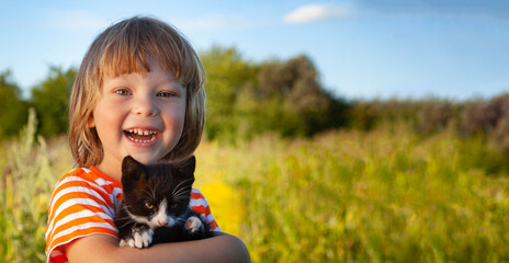 Happy kid with a kitten in her arms in nature