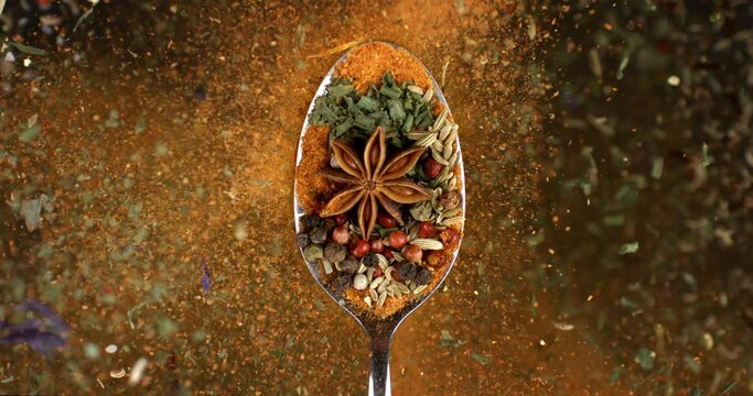 Super slow motion macro of dry pink flavorful aromatic peppercorn seeed and other spices mix falling down from silver spoon isolated on soft dark background.