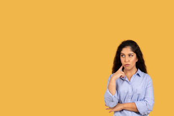 Pensive latin young brunette woman in casual think, look up at free space, create idea