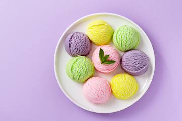 Pastel colored ice cream scoops on white plate, top view.