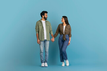 Romantic millennial indian couple posing on blue studio background