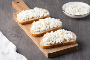 Bread with curd cheese on wooden board