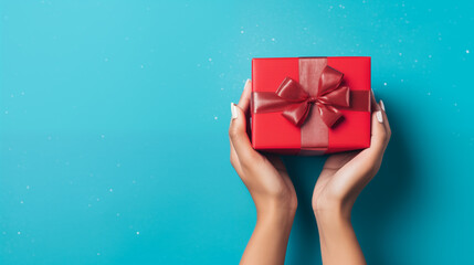 Woman's Hands Giving Red Present on Blue Background with Copy space
