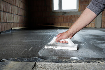 Smoothing concrete screed during house construction.