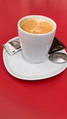 White cup with café con leche on a table with a red background