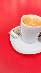 White cup with café con leche on a table with a red background