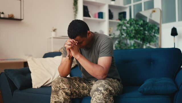 Depressed African American military praying with rosary, asking God for help