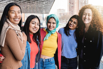 Diverse female friends having fun togehter on city street. Group of multiracial people smiling and...