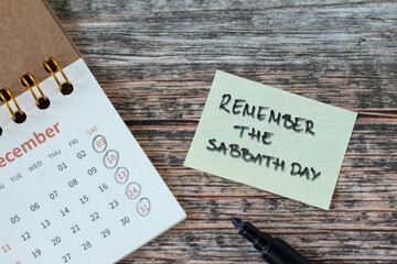 Remember the Sabbath Day, handwritten verse on note and calendar on wooden table. Christian holy...