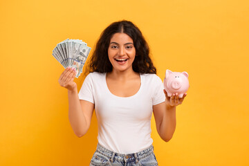 Emotional young woman with piggybank and cash