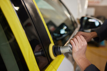 The mechanic works with a grinding tool. Sanding of car elements. Garage painting car service....