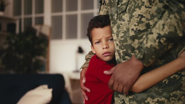 Sad boy hugging soldier dad, saying goodbye to father leaving for the military