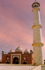 Architectural buildings around Taj Mahal - Tall minaret in front of the red sandstone building Jawab at dusk in Agra, India