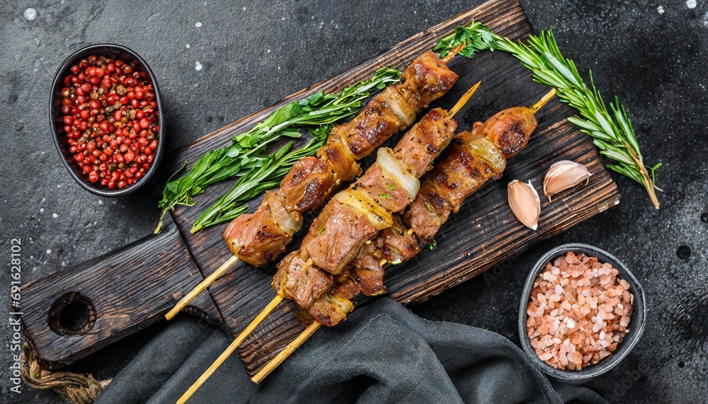 Wall mural Grilled meat skewers, shish kebab on black background, top view