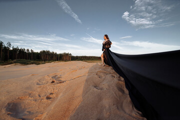 Elegant woman in flowing dress on sand dune, evoking freedom and wanderlust. Ideal for fashion,...