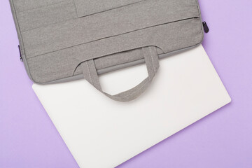 Grey stylish laptop bag with device on color background,top view
