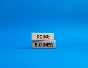 Obraz premium Doing Business symbol. Concept word Doing Business on wooden blocks. Beautiful blue background. Business and Doing Business concept. Copy space