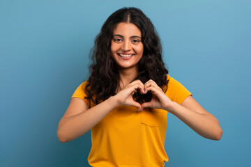 Cute young indian woman showing heart gesture