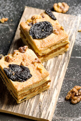 Cake with prunes and nuts. Pieces of delicious cake on a wooden plate. Decoration for the New Year and Christmas table.