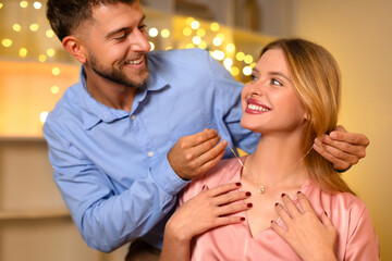Man affectionately gifting a necklace to a delighted woman - obrazy, fototapety, plakaty