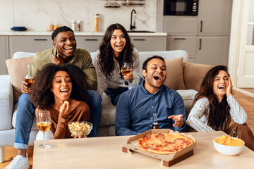 Happy group of diverse friends watching comedy film at home