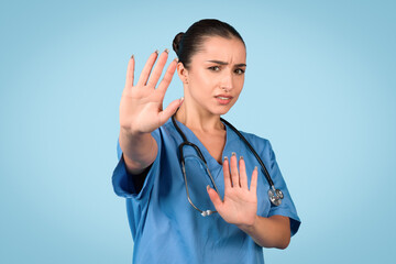 Nurse gesturing stop with hand, blue background