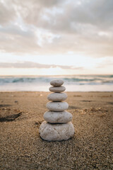 Fototapeta na wymiar A cairn of smooth stones stacked on the sand symbolizes balance and tranquility by the sea