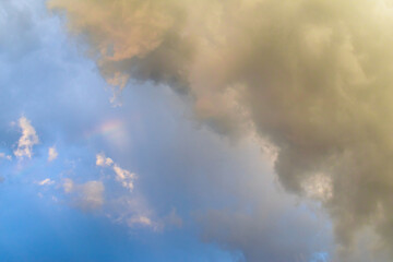 Background of summer cloudy sky with tiny rainbow