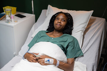 African woman lies in her hospital bed, calmly looking at the camera, showing her strength during...
