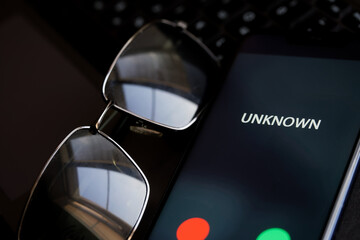 Smartphone with unknown unidentified incoming call with sunglasses on the laptop keyboard. Problems...