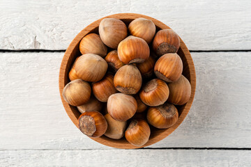 Overhead shot of hazelnuts in bowl on white wooden table. Healthy snacks