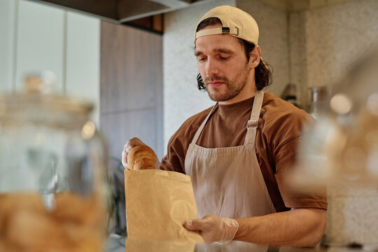 Caucasian male worker carefully packing takeaway order at bakery