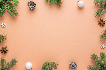 Christmas frame on peach fuzz color background. Composition made of fir tree, Christmas ornament,...