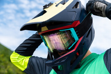 Guy adjusting motorcycle motocross helmet with goggles, close-up shot of relaxing while riding bike...