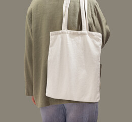 Natural textile eco tote bag mock up on shoulder. Woman back with green shopper