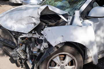 car after an accident, severed wires dangle from the front of damaged vehicle, illustrating the...
